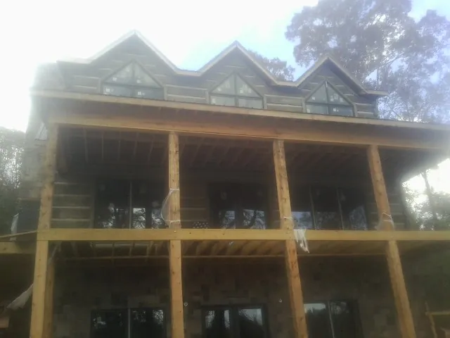 Dormers and porch framing on a large log home under construction — Roof Coating work by our crew in Hellertown