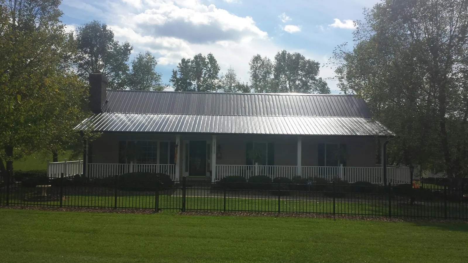 Gray metal roof on a brick ranch with a full width front porch — Gutter Guard Installation work by our crew in Hellertown