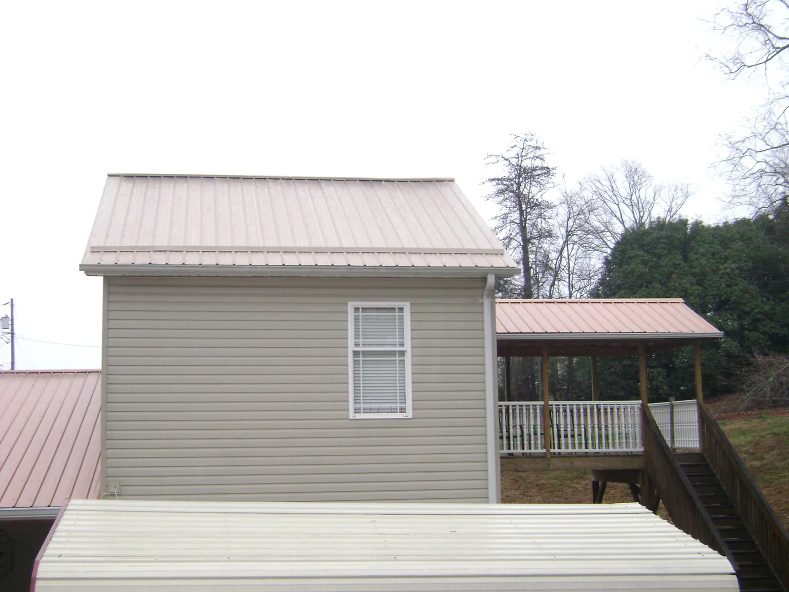 Tan metal roofs on a two story addition and attached porch, from a Roof Replacement job in Hellertown