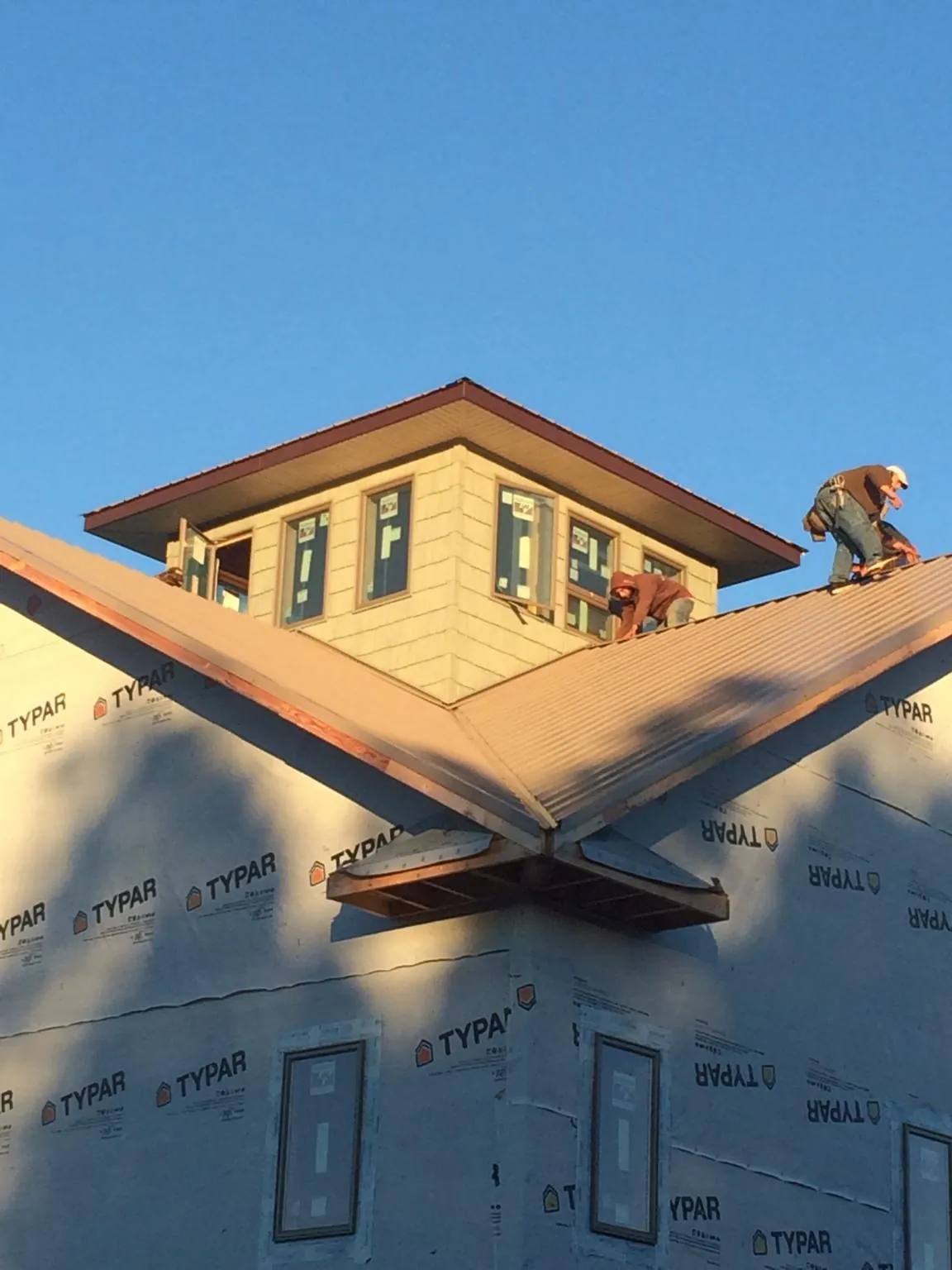 Roofers working around a rooftop cupola on a new metal roof at sunset — Roof Waterproofing in Hellertown by Roofing Brothers
